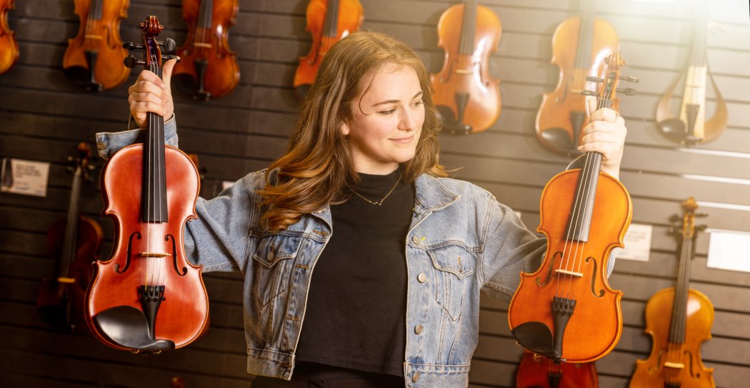 Person Holding Different Sized Violins